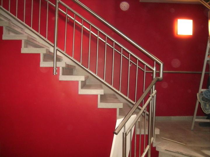 Inox trapleuning in een trappenhal met rode wand